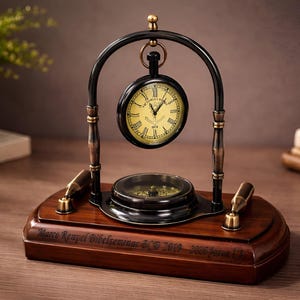 Op de afbeelding: Een bureauklok in vintage-stijl met een kompas en twee decoratieve messing buizen. De klok heeft een zwart frame, een gele wijzerplaat en een zwarte boog. De basis is gemaakt van donker hout. Het is een decoratief item.