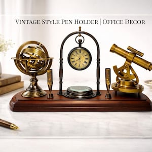 Op de afbeelding: Een bureau-organizer op een donkerhouten voet met een messing armillarium, een hangend zakhorloge met een kompasvoet en een kleine messing telescoop. De tekst VINTAGE STYLE PEN HOLDER | OFFICE DECOR staat boven de objecten afgebeeld.