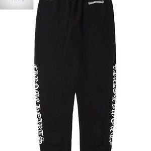 May include: Black sweatpants with white text reading "Chrome Hearts" vertically down the sides. The pants have a drawstring waist and small logos near the top. A casual, comfortable style.