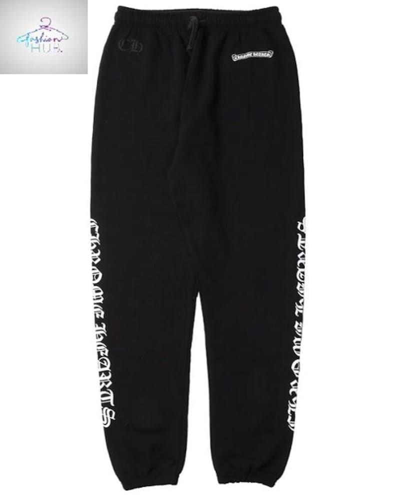 May include: Black sweatpants with white text reading "Chrome Hearts" vertically down the sides. The pants have a drawstring waist and small logos near the top. A casual, comfortable style.