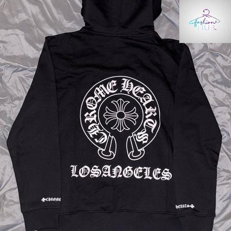 May include: Black hoodie with a white graphic on the back that says "CHROME HEARTS LOSANGELES". The hoodie has a drawstring hood and a small logo on the left sleeve.