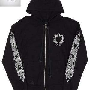 May include: Black zip-up hoodie with white decorative designs on the sleeves and a white logo on the chest. The hoodie has a hood and a silver zipper. The sleeves feature a detailed, symmetrical pattern.