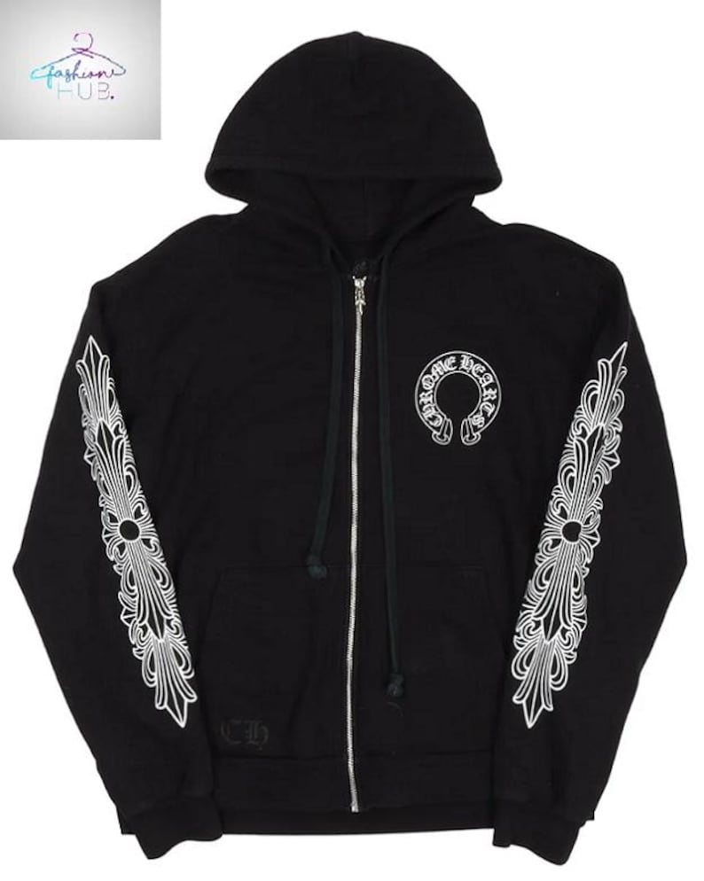 May include: Black zip-up hoodie with white decorative designs on the sleeves and a white logo on the chest. The hoodie has a hood and a silver zipper. The sleeves feature a detailed, symmetrical pattern.