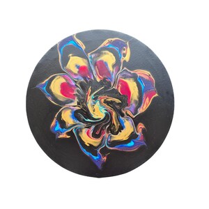 May include: Abstract floral painting on a black circular canvas. The flower design features a swirl of colors including gold, blue, red, and yellow. The artwork is set against a white background.