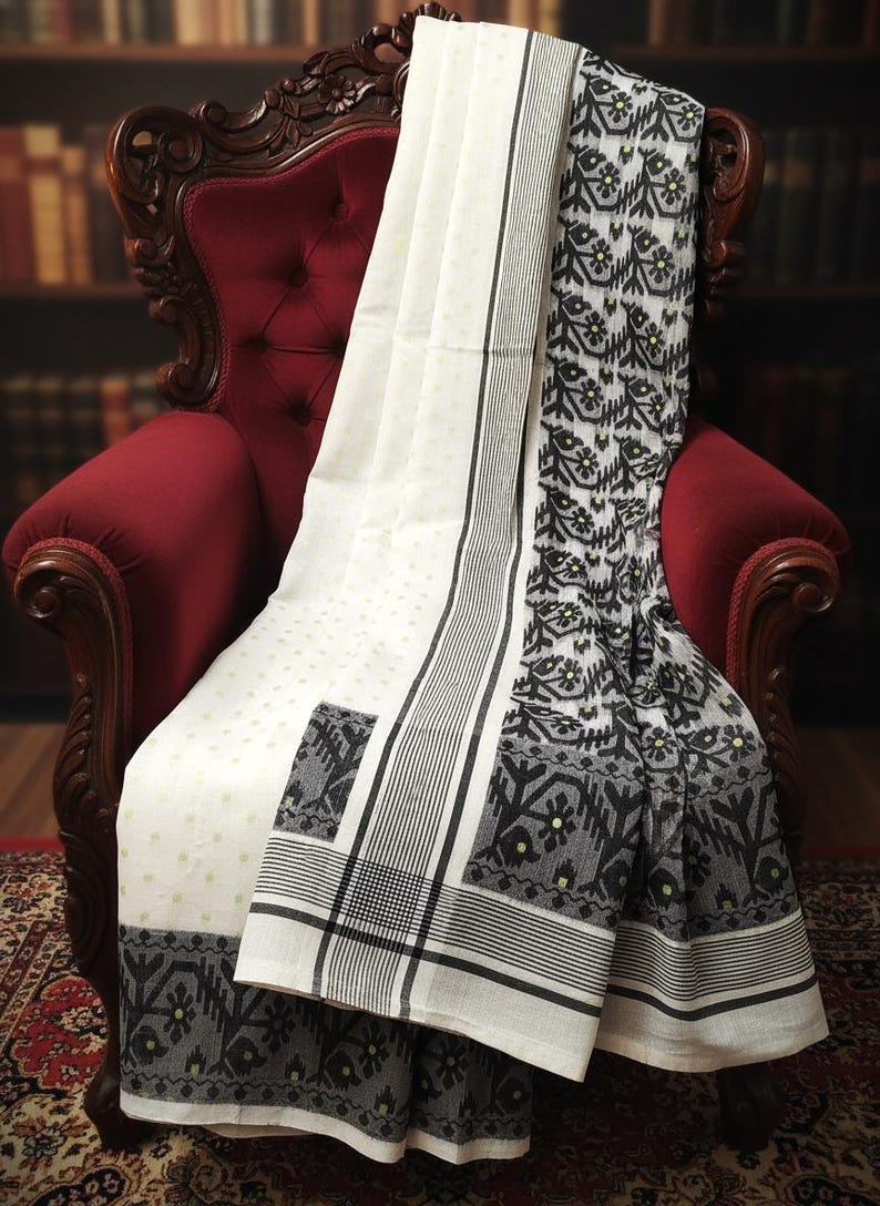 May include: A white and black patterned textile is draped over a red upholstered chair. The textile features a repeating floral design in black and gray, with a white background. The chair is ornate with dark wood detailing.