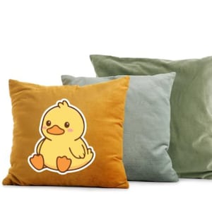 K&ouml;nnte beinhalten: Drei dekorative Kissen in Gold-, Grau-Blau- und Olivgr&uuml;nt&ouml;nen. Das goldene Kissen zeigt eine Cartoon-Enten-Grafik. Die Kissen sind aus einem weichen, strukturierten Stoff gefertigt, ideal f&uuml;r mehr Komfort und Stil in jedem Wohnraum.