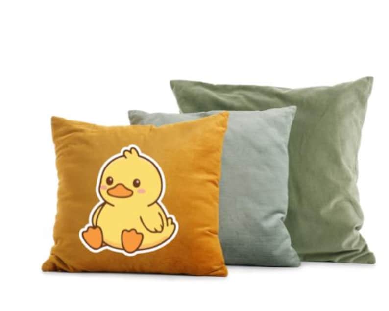 K&ouml;nnte beinhalten: Drei dekorative Kissen in Gold-, Grau-Blau- und Olivgr&uuml;nt&ouml;nen. Das goldene Kissen zeigt eine Cartoon-Enten-Grafik. Die Kissen sind aus einem weichen, strukturierten Stoff gefertigt, ideal f&uuml;r mehr Komfort und Stil in jedem Wohnraum.