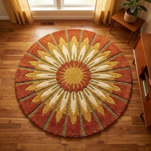 May include: A circular rug with a floral pattern. The rug has a yellow centre with petals in yellow, cream, and orange. Green accents separate the petals. The rug is placed on a wooden floor.