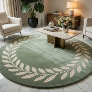 May include: A circular, sage green rug featuring a cream-coloured laurel wreath pattern around the edge. The rug is in a living room with neutral furniture and decor. The rug's diameter is approximately 244 cm.