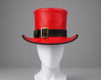 May include: A bright red top hat featuring a smooth finish and a wide, curved brim. The hat is accented with a black leather-like band that wraps around the base, secured by a rectangular brass-toned buckle centered at the front of the crown.