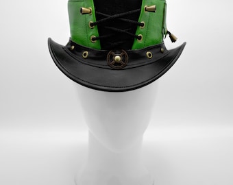 May include: A black top hat featuring a vibrant green leather band with black lace-up detailing, brass-toned eyelets, and a central gear-shaped metal emblem on the brim. The hat has a structured crown and a curved brim with brass studs.