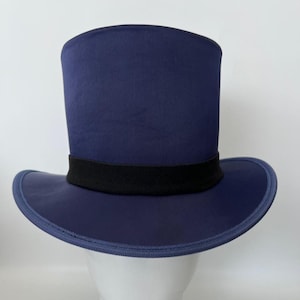 Puede incluir: Un sombrero de copa azul marino con una banda negra. El sombrero tiene un ala ancha y una copa cil&iacute;ndrica alta. El sombrero se exhibe sobre una cabeza de maniqu&iacute; blanca.