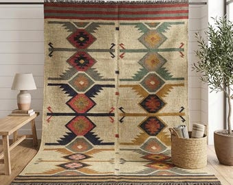 May include: A large rectangular area rug featuring a cream-colored base with a repeating geometric pattern in shades of red, navy blue, mustard yellow, green, and gray. The rug has a fringed edge at the top and bottom and a horizontal striped border.