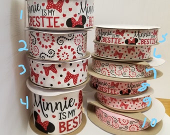 May include: A stack of ten white ribbon spools with red and black polka dots, hearts, and swirls. The ribbon features the text "Minnie is my bestie" and "Minnie is my best".
