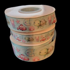 May include: Three spools of blue ribbon with a white background and a pattern of sea turtles, fish, and coral.