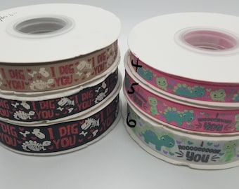 May include: Six spools of ribbon with dinosaur and heart designs. The ribbon is in three different color combinations: brown and white, black and white, and pink and green. The ribbon has the text "I Dig You" printed on it.