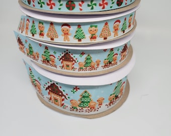 May include: Four spools of blue and white ribbon with a Christmas gingerbread house and gingerbread man pattern. The ribbon is on a white background.