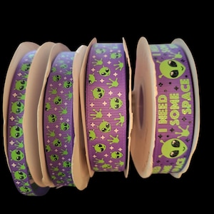May include: Purple ribbon with green alien faces and the text "I need some space" repeated on the ribbon.