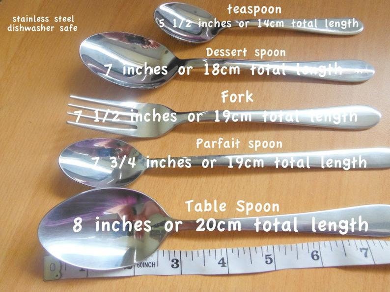 May include: A set of five stainless steel utensils, including a teaspoon, dessert spoon, fork, parfait spoon, and table spoon. The utensils are laid out in order of size, with the teaspoon at the top and the table spoon at the bottom. The utensils are all dishwasher safe. The text on the image reads: "stainless steel dishwasher safe", "teaspoon 5 1/2 inches or 14cm total length", "Dessert spoon 7 inches or 18cm total length", "Fork 7 1/2 inches or 19cm total length", "Parfait spoon 7 3/4 inches or 19cm total length", "Table Spoon 8 inches or 20cm total length".