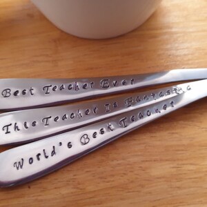 May include: Three silver spoons with engraved messages: "Best Teacher Ever", "This Teacher Is Fantastic", and "World's Best Teacher".