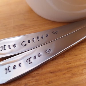 Pu&ograve; includere: Due cucchiai d'argento con cuori incisi e il testo "His Coffee" e "Her Tea".