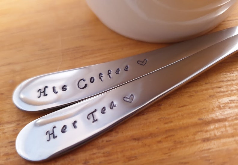 Pu&ograve; includere: Due cucchiai d'argento con cuori incisi e il testo "His Coffee" e "Her Tea".