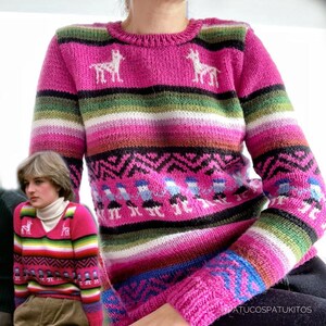 May include: A pink knit sweater with a crew neck and long sleeves. The sweater features a striped pattern in shades of pink, green, white, and blue. White llama figures are on the chest. The sleeves have a patterned design in blue and pink.