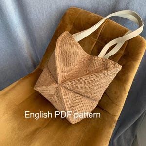 Puede incluir: Un bolso de ganchillo color canela con un patrón geométrico de chevrón y dos correas anchas de color claro. El texto "English PDF pattern" está impreso en blanco en la parte inferior de la imagen, indicando que es un documento digital.
