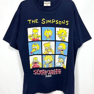 May include: A navy blue short-sleeve t-shirt featuring a graphic print of The Simpsons characters making various expressions. The text reads THE SIMPSONS at the top and SCARY FACES at the bottom. The shirt has a Redwood brand label at the neck.