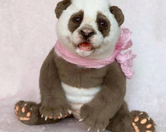 May include: A plush panda bear with a white face and body, brown ears, and brown fur on its arms and legs. The panda is wearing a pink scarf and has an open mouth. The bear is sitting with its legs spread.