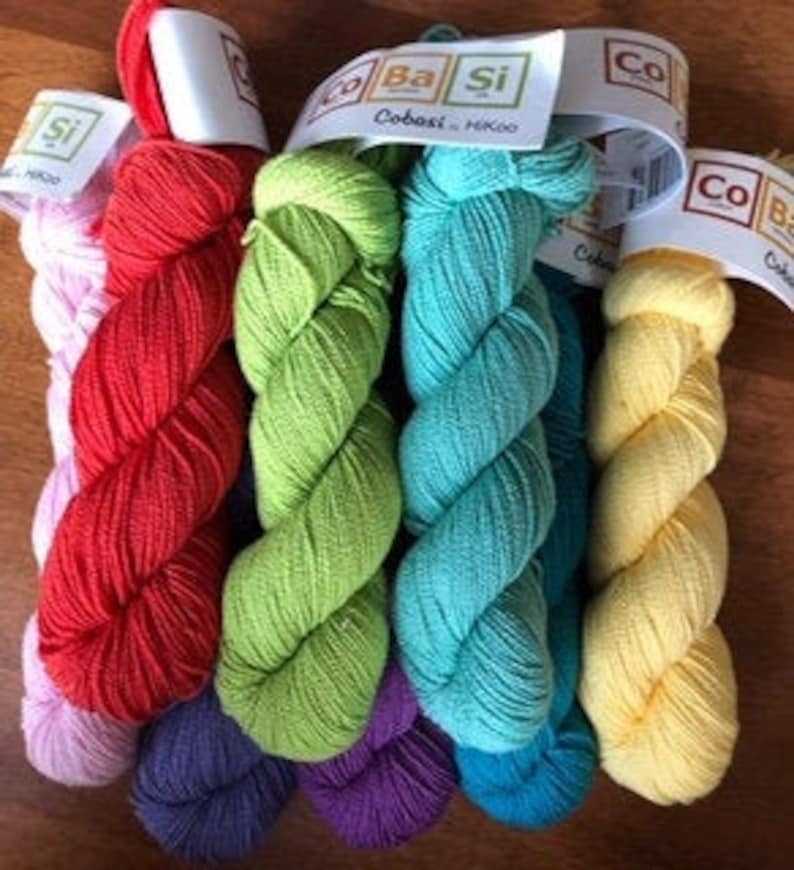May include: Six skeins of Cobasi & Mako yarn in various colors, including pink, red, green, turquoise, yellow, and purple. The yarn is labeled "Cobasi & Mako" and is packaged in individual skeins.