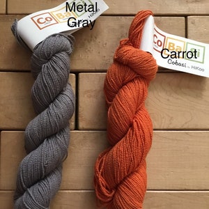 May include: Two skeins of Cobasi yarn, one in a gray color called "Gun Metal" and one in an orange color called "Carrot". Both skeins are labeled "Cobasi by HiKoo."