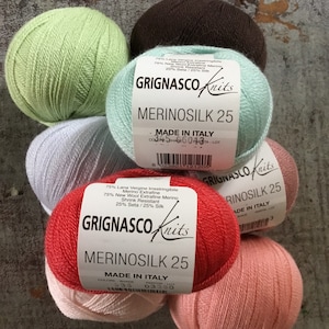 May include: Five balls of yarn in various colors, including green, light blue, brown, red, and pink. Each ball has a label that reads "Grignasco Knits" and "Merinosilk 25" with the text "Made in Italy".