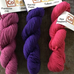 May include: Three skeins of Cobasi yarn in the colors Framboise, Red Hat Purple, and Ripe Raspberry. The yarn is a blend of cotton, bamboo, and silk.