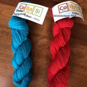 May include: Two skeins of yarn, one turquoise blue and one red. The yarn is labeled "Deep Turquoise" and "CoBaSi" and "VaVaVaVoom Red" and "CoBaSi".