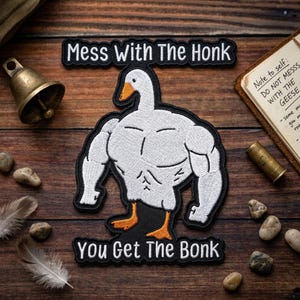 May include: Embroidered patch featuring a muscular goose with the text "Mess With The Honk, You Get The Bonk." The goose is white with orange feet and beak, outlined in black. The patch is on a wooden surface.