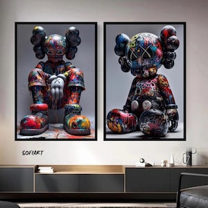 Peut inclure: Deux impressions d'art encadrées représentant des personnages colorés de style graffiti avec de grandes têtes et des yeux barrés. Les personnages sont assis, avec des mains gantées et des vêtements détaillés. L'œuvre est exposée sur un mur neutre au-dessus d'un meuble moderne.