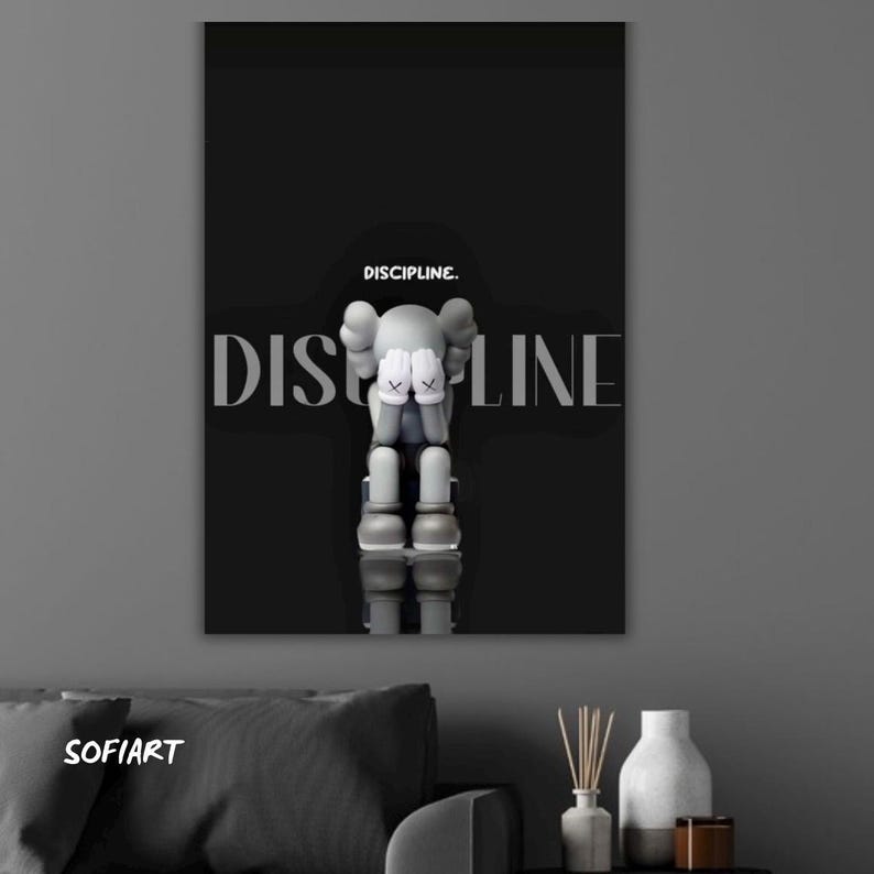 May include: Art print with a black background, featuring a grey figure with hands covering its face, and the word "DISCIPLINE" in large, white letters. The word "DISCIPLINE." is written above the figure. The print has a minimalist design.
