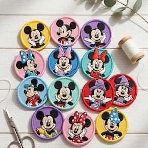 May include: A selection of embroidered Mickey and Minnie Mouse patches. Each circular patch has a different coloured border and shows the characters in various poses and outfits. A pair of scissors and a reel of thread are also in the image.