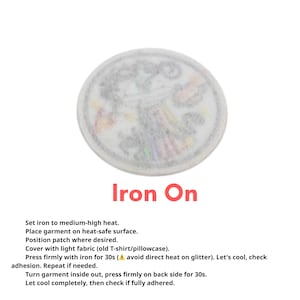 May include: A circular iron-on patch with a faded, colorful design. The patch is white with a blurred image and the words "Iron On" in red. Instructions for application are listed below the patch.