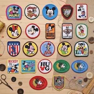 May include: A collection of colorful Disney character patches, including Mickey Mouse, Minnie Mouse, and other characters. The patches are in various shapes and sizes, with embroidered details and text. Some patches feature the text "Mickey Mouse" and "Santa Fe".