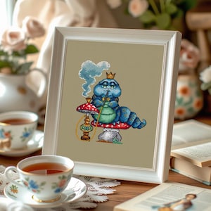 May include: A framed cross-stitch featuring a blue caterpillar wearing a crown and smoking a hookah while sitting on a mushroom. The image is surrounded by teacups, books, and flowers, creating a whimsical, vintage aesthetic.