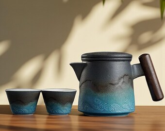 May include: A ceramic tea set featuring a teapot and two cups. The teapot has a black lid and a wooden handle. The set is predominantly black and blue with a wave pattern. The cups share a similar design.