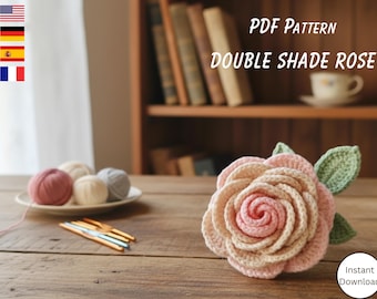 May include: A crocheted rose in shades of pink and beige with green leaves. The image also shows yarn balls, crochet hooks, and the text "PDF Pattern Double Shade Rose".