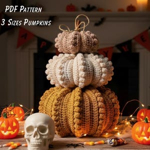Op de afbeelding: Een stapel van drie gehaakte pompoenen in beige, crème en mosterdgeel. De pompoenen zijn versierd met een getextureerde bobbelsteek. De afbeelding bevat de tekst "PDF PATTERN 3 SIZES PUMPKINS".