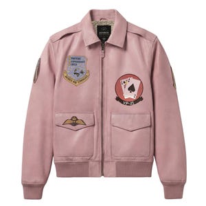 Pu&ograve; includere: Un giubbotto bomber in pelle rosa chiaro con chiusura a zip, due tasche con patta, polsini e orlo a coste. Il petto presenta toppe ricamate, tra cui un emblema dello Strategic Reconnaissance Center e un disegno di carte da gioco con VP-21.