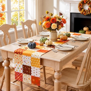 May include: A rectangular table runner featuring a patchwork design of autumn-themed patterns including leaves, polka dots, and plaid in shades of orange, yellow, brown, and white, displayed on a wooden dining table with seasonal decor.
