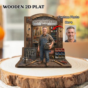 May include: Wooden 2D plat with a craftsman figure, tools, and the text "Happy Father's Day David." The image includes a toolbox, a miniature American flag, and a space for a custom photo. The background is a wooden workshop.