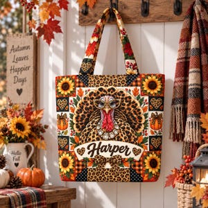 May include: A tote bag featuring a central turkey illustration wearing glasses and a necklace, surrounded by sunflowers, pumpkins, and leopard print patterns. The name Harper is printed in a script font on a banner below the turkey.