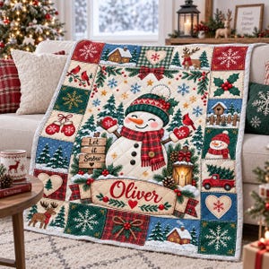 Könnte beinhalten: Eine gesteppte Weihnachtsdecke mit einem zentralen Schneemann mit Mütze und Schal, umgeben von Feldern mit Rentieren, Tannen, Schneeflocken und einem Holzschild mit der Aufschrift Let it Snow. Ein Banner unten zeigt den Namen Oliver.